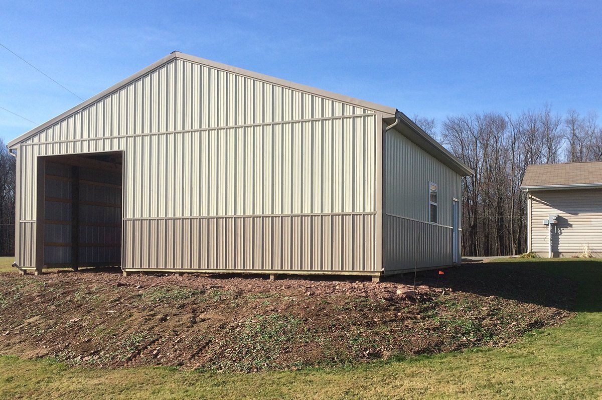 A metal building is sitting in the middle of a grassy field.