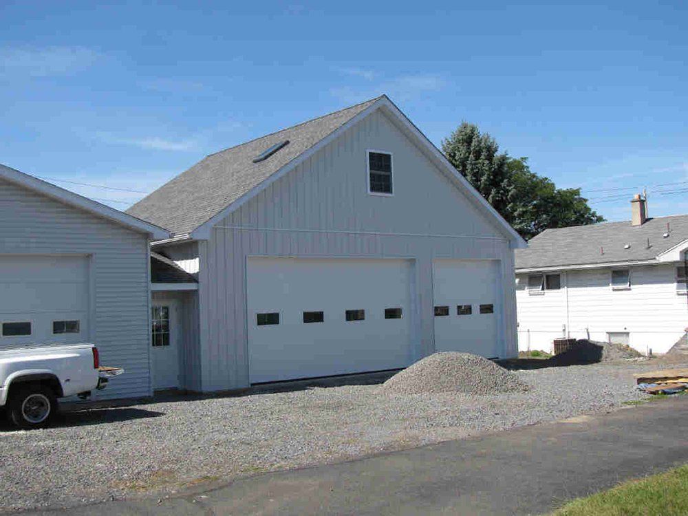 A white truck is parked in front of a white garage.