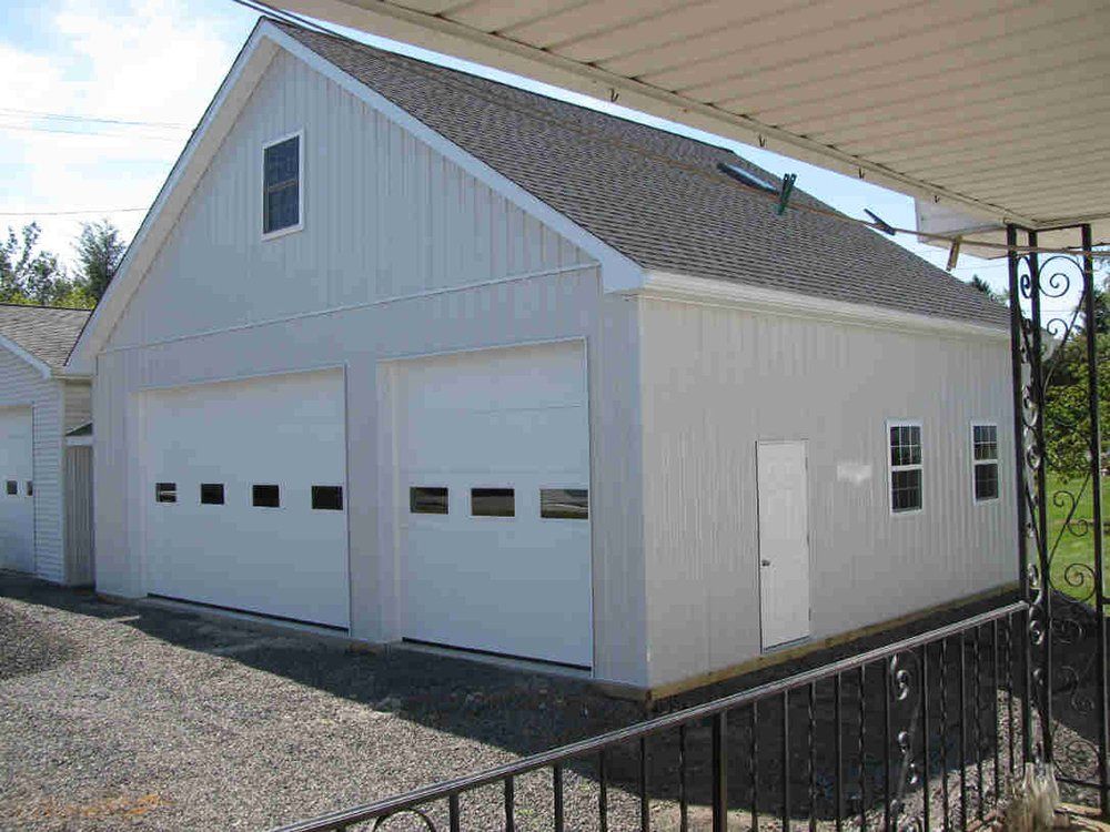 A white garage with two garage doors and a roof.