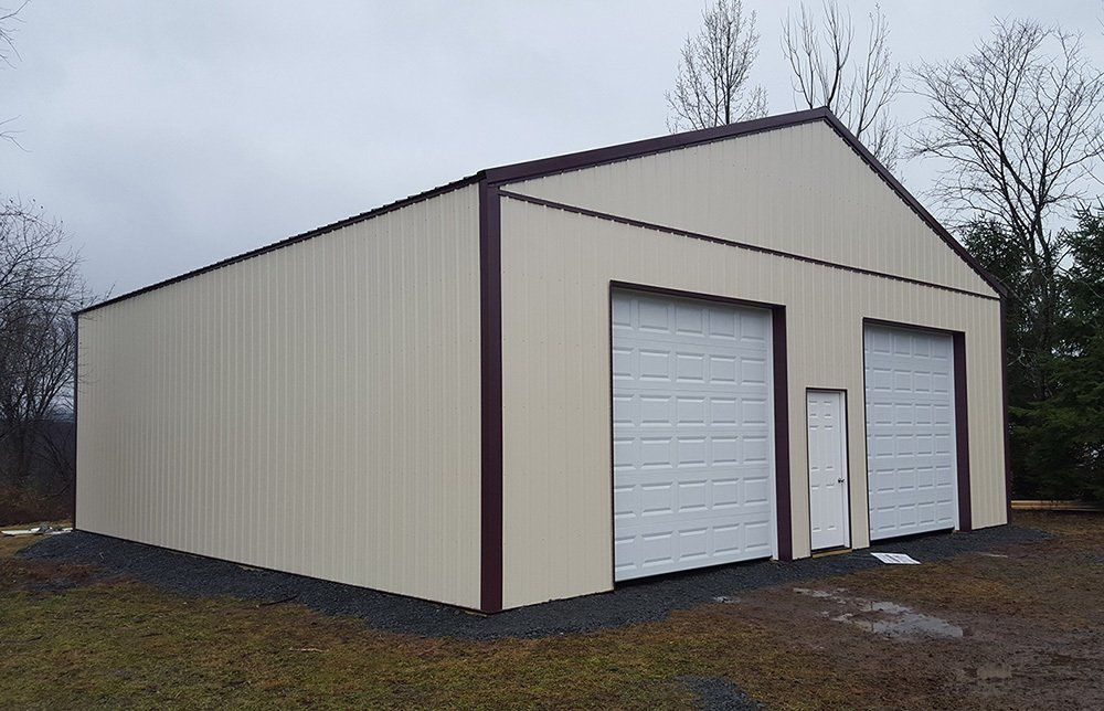 A large metal building with two garage doors and a doorway.
