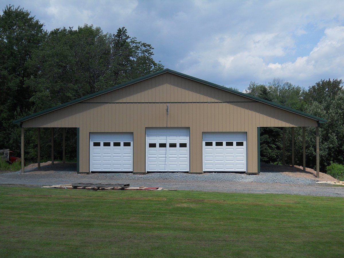 A brown building with white garage doors and a green roof