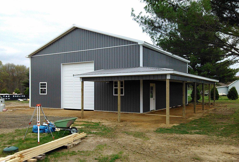 A gray metal building with a white roof and a porch.