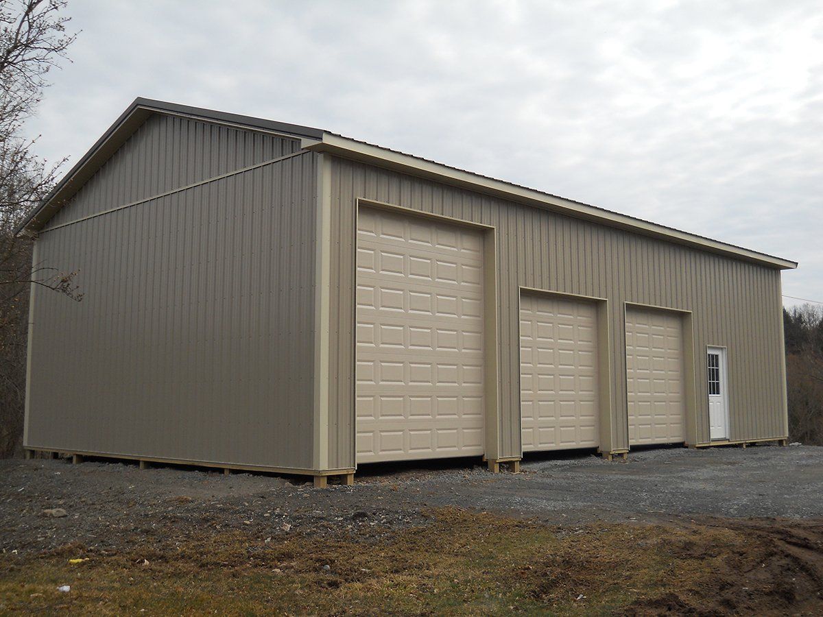 A large metal building with three garage doors and a white door