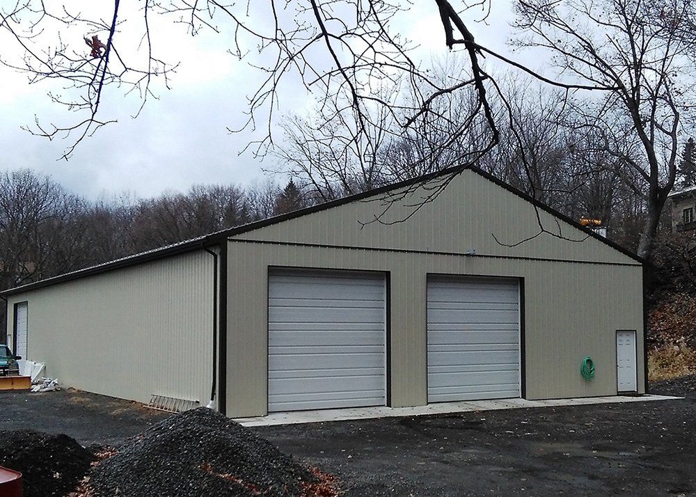 A large building with two garage doors is surrounded by trees