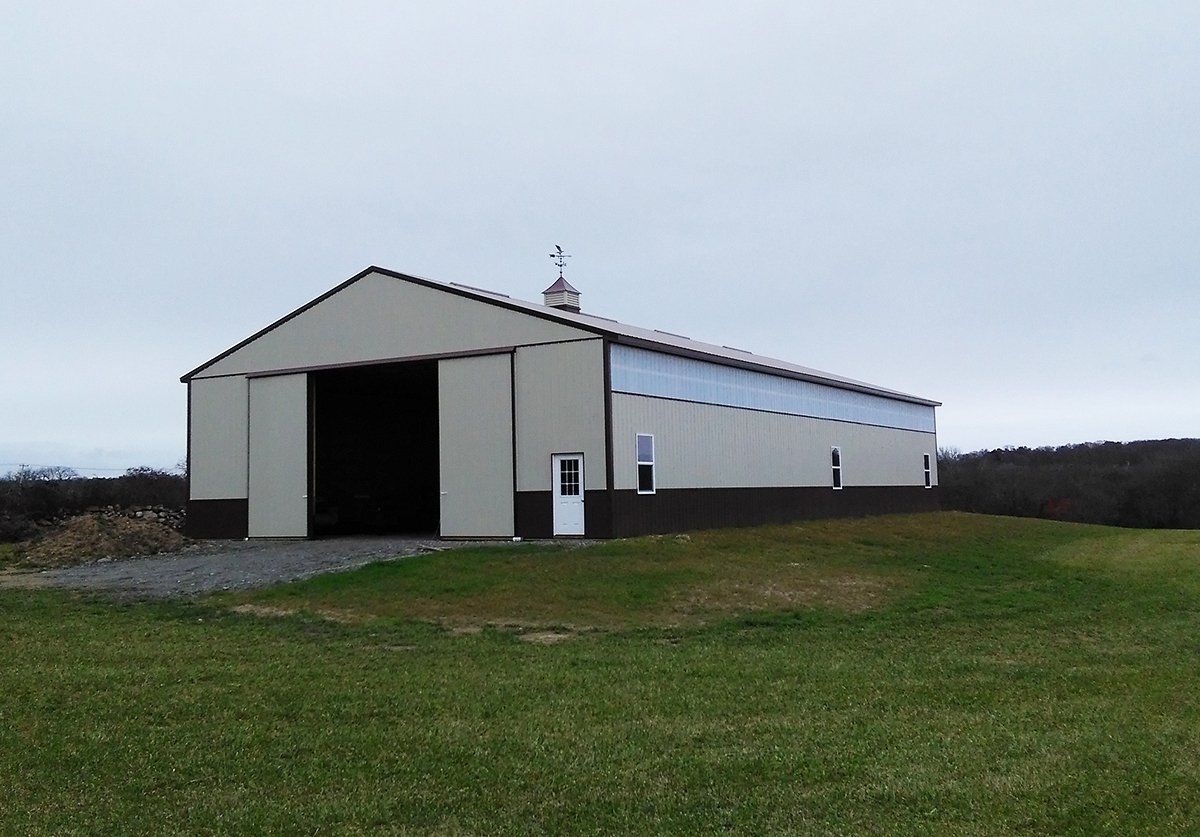 A large barn is sitting in the middle of a grassy field.