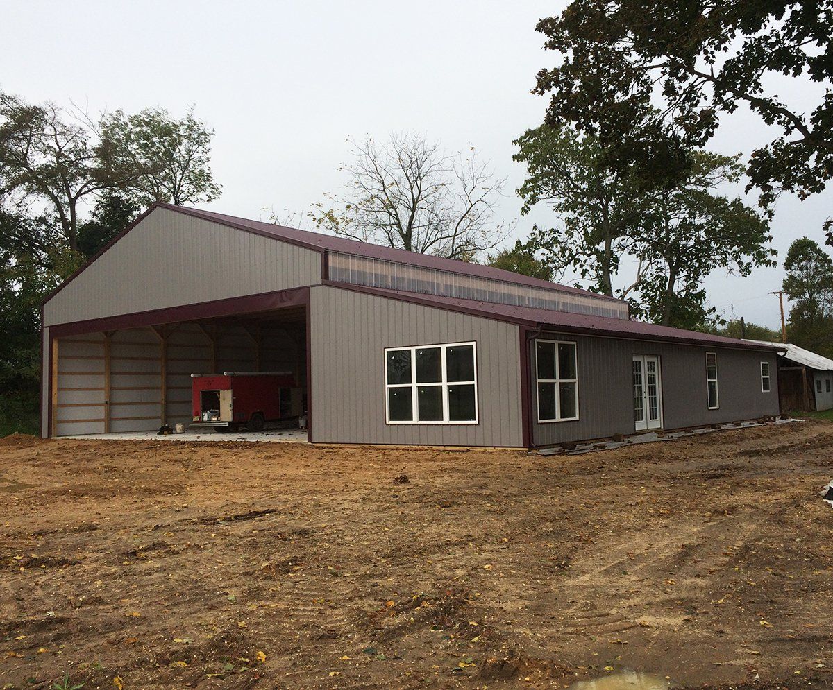 A large building with a red roof is sitting in the middle of a dirt field.