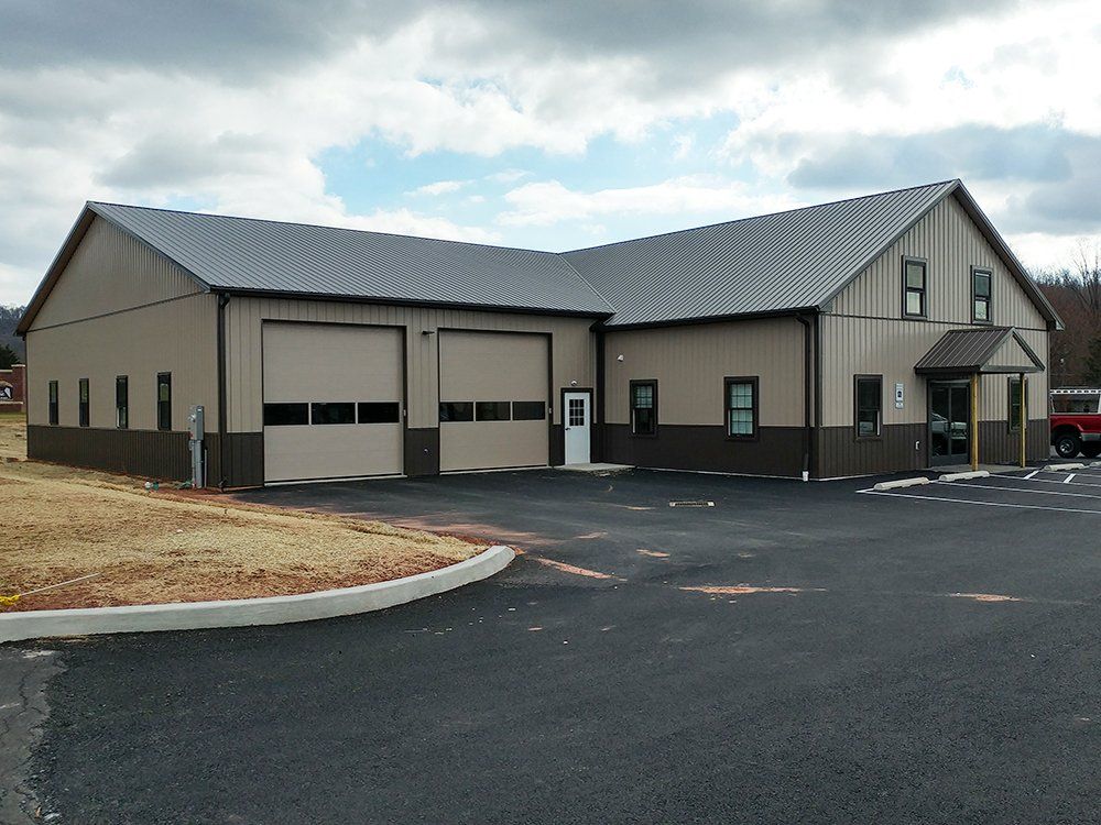 A large building with two garage doors and a red truck parked in front of it.