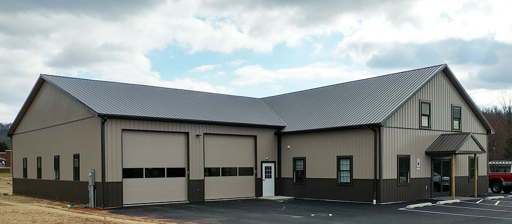A large building with two garage doors and a gray roof