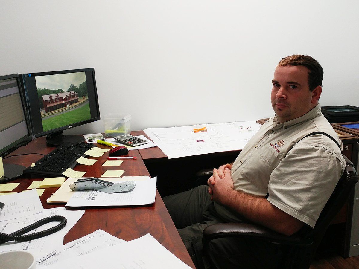 A man sits at a desk in front of two computer monitors