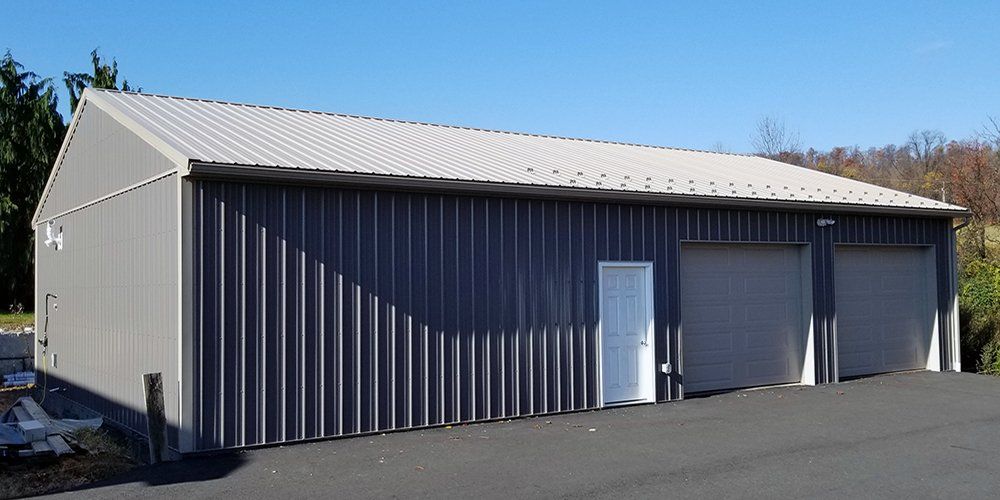 A large metal building with two garage doors and a white roof.