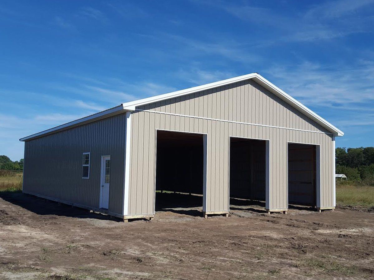 A large building with three doors is sitting in the middle of a dirt field.