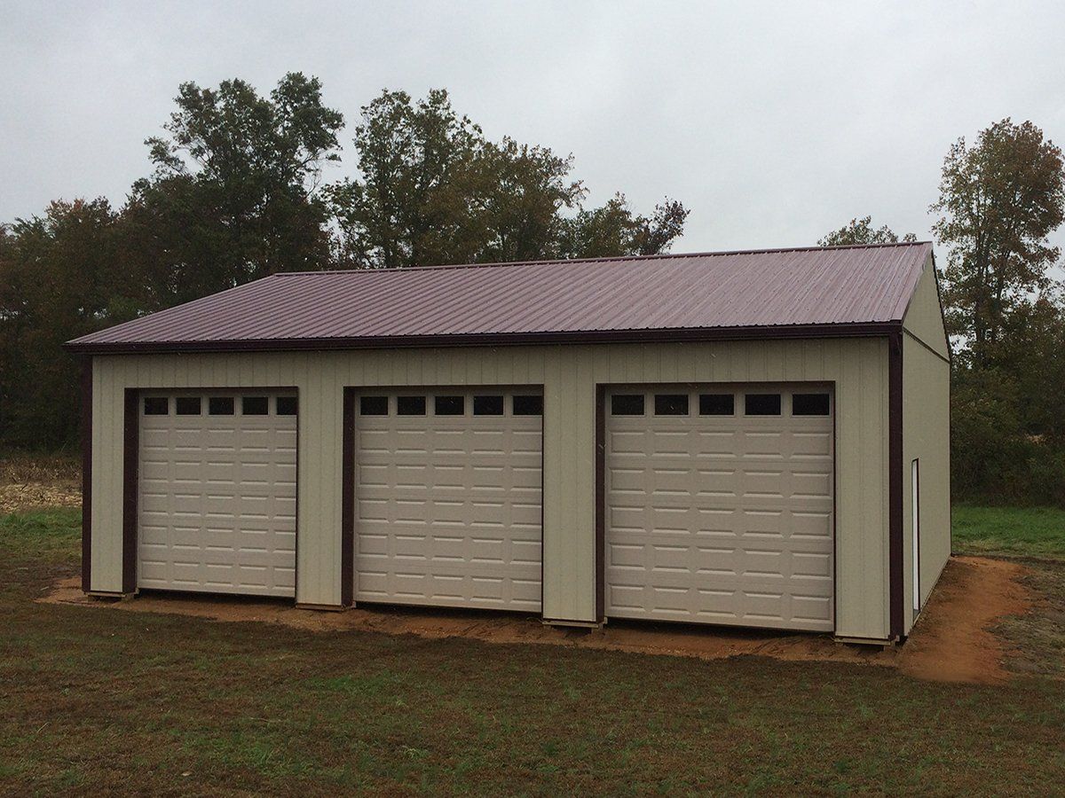 A garage with three garage doors and a brown roof