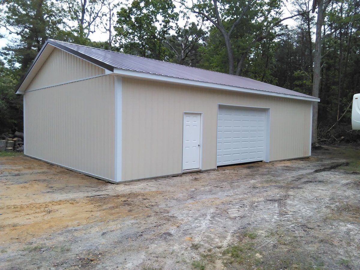 A garage with a white door and a purple roof is sitting in the middle of a dirt field.