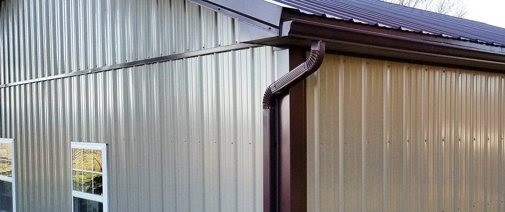 A metal building with a brown gutter on the side of it.