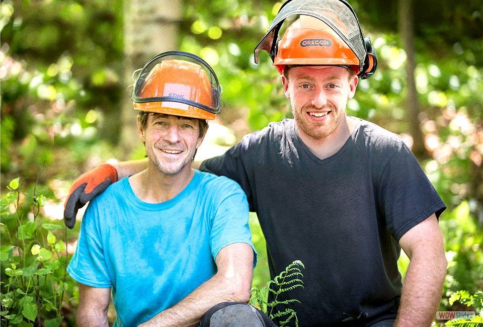 Deux hommes portant des casques de sécurité posent pour une photo dans les bois.