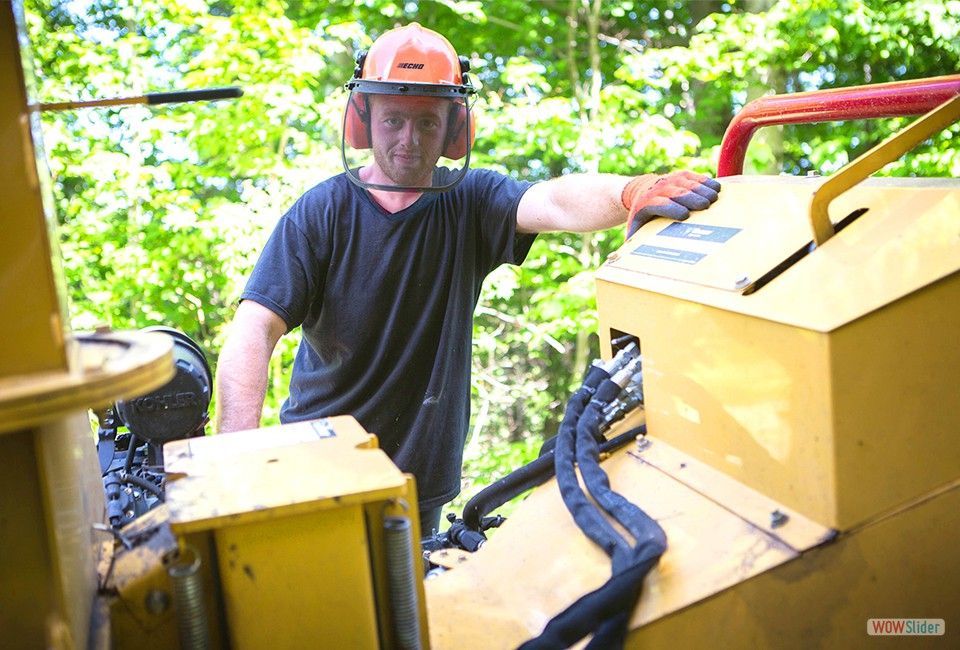 Un homme portant un casque et des cache-oreilles travaille sur une machine.