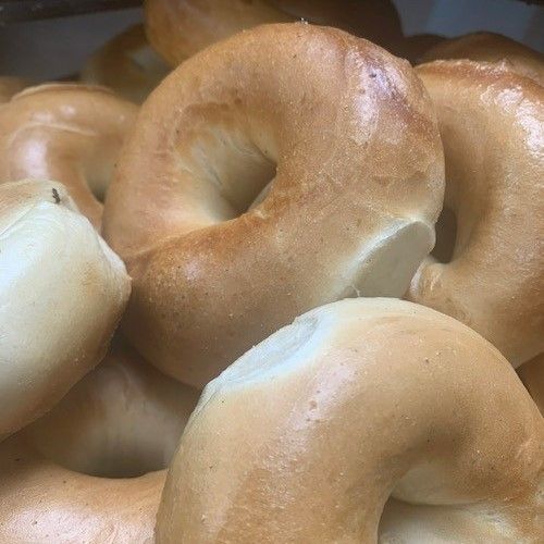 A Bagel With Butter On It Sits On A Yellow Surface - Mahopac, NY - Our Town Bagels & Bakery