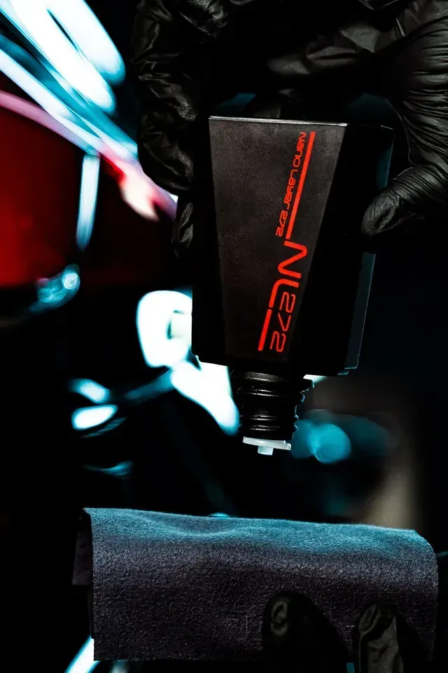 A gloved hand dispenses a liquid product, labeled 