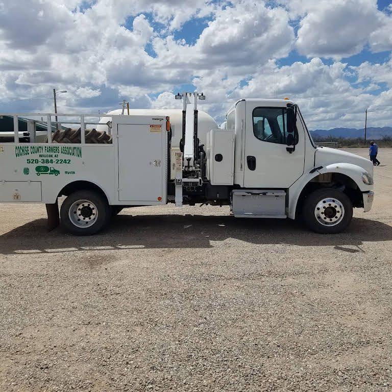 a white truck is parked in a dirt field with a phone number on the side