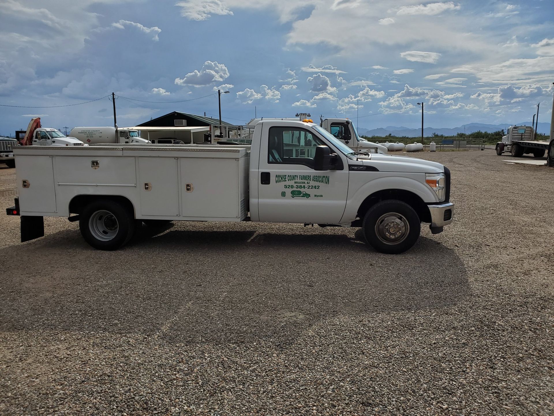 a white utility truck is parked in a gravel lot .