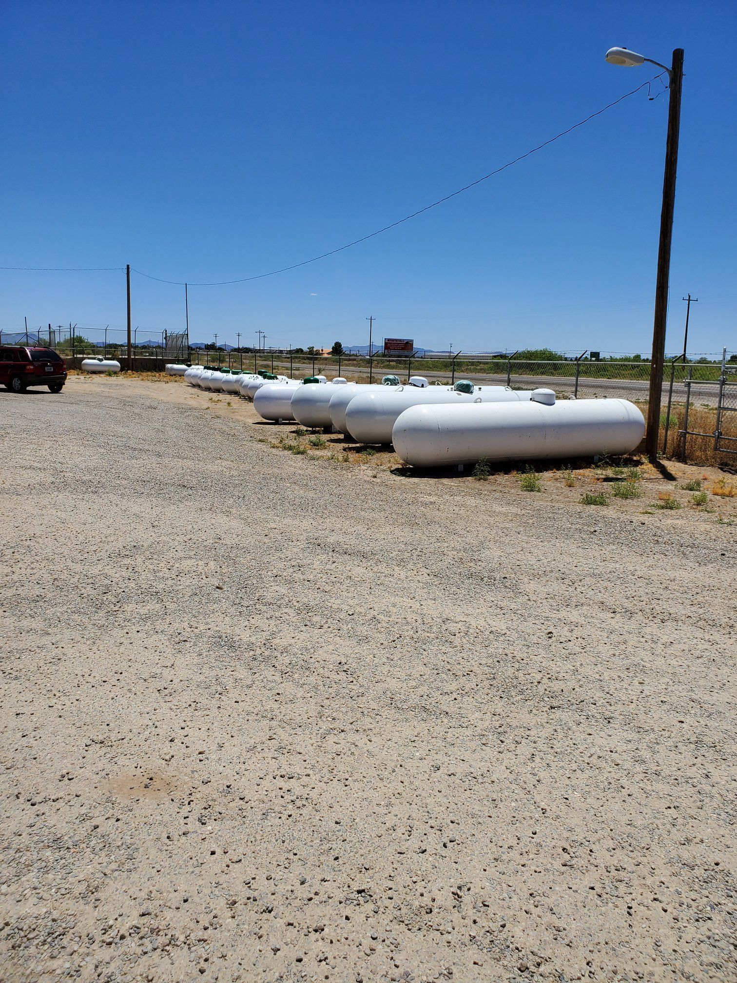 a row of propane tanks are lined up in a dirt lot .