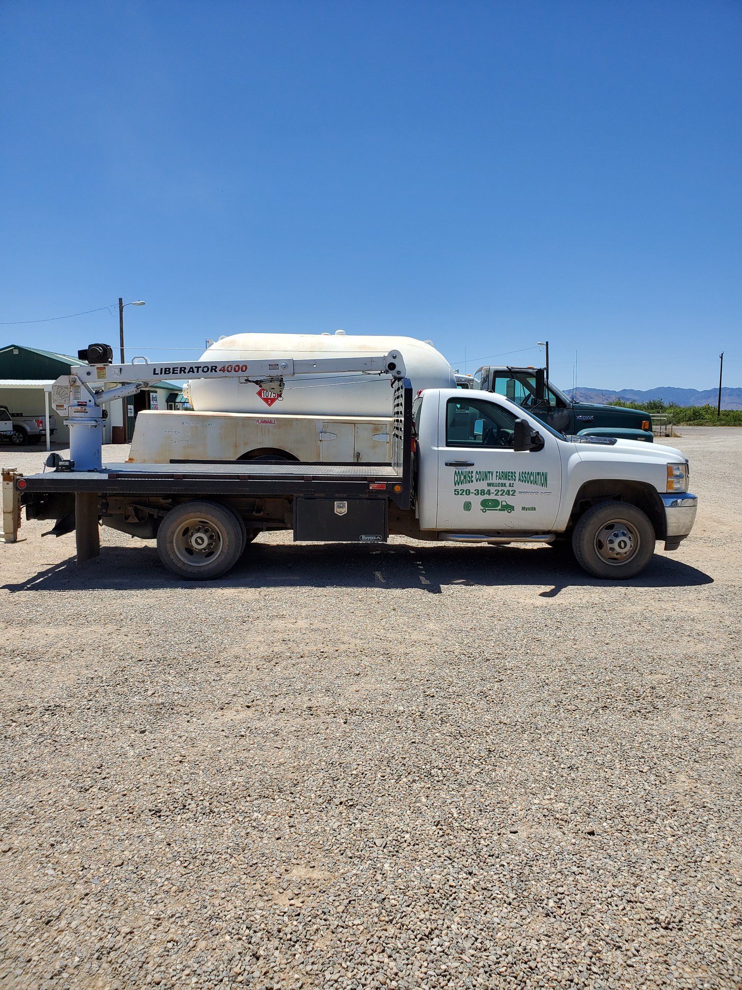 a white truck is parked in a gravel lot .