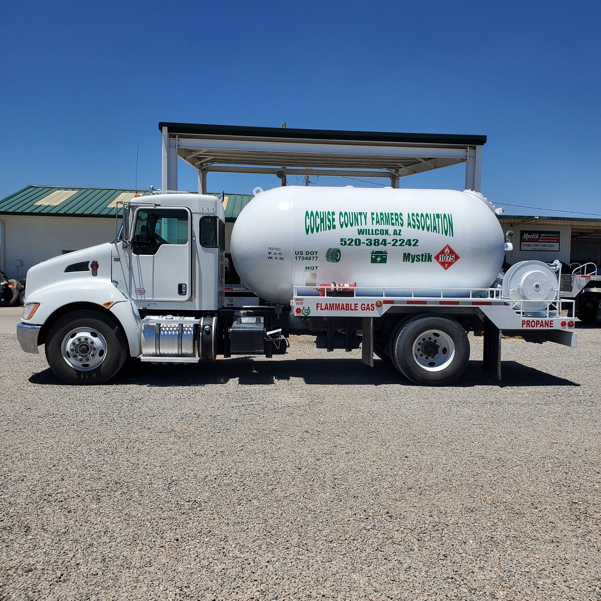 a white tanker truck is parked in a gravel lot