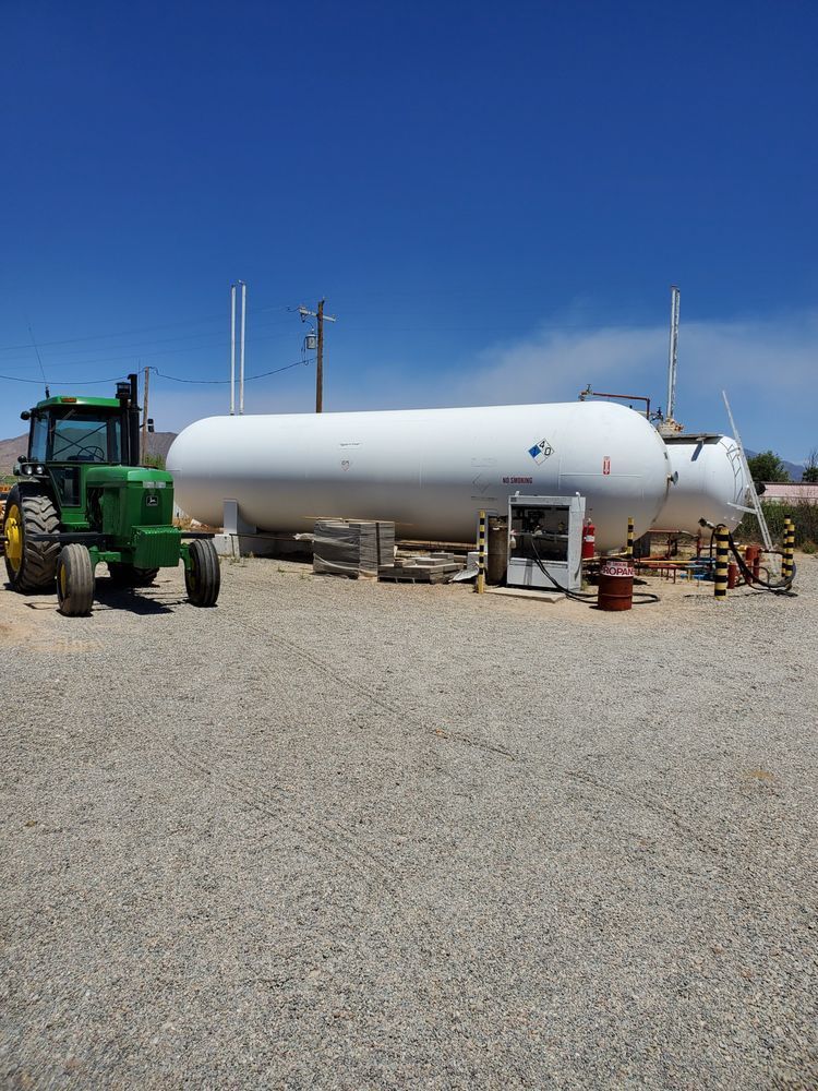 a green tractor is parked next to a large white tank .