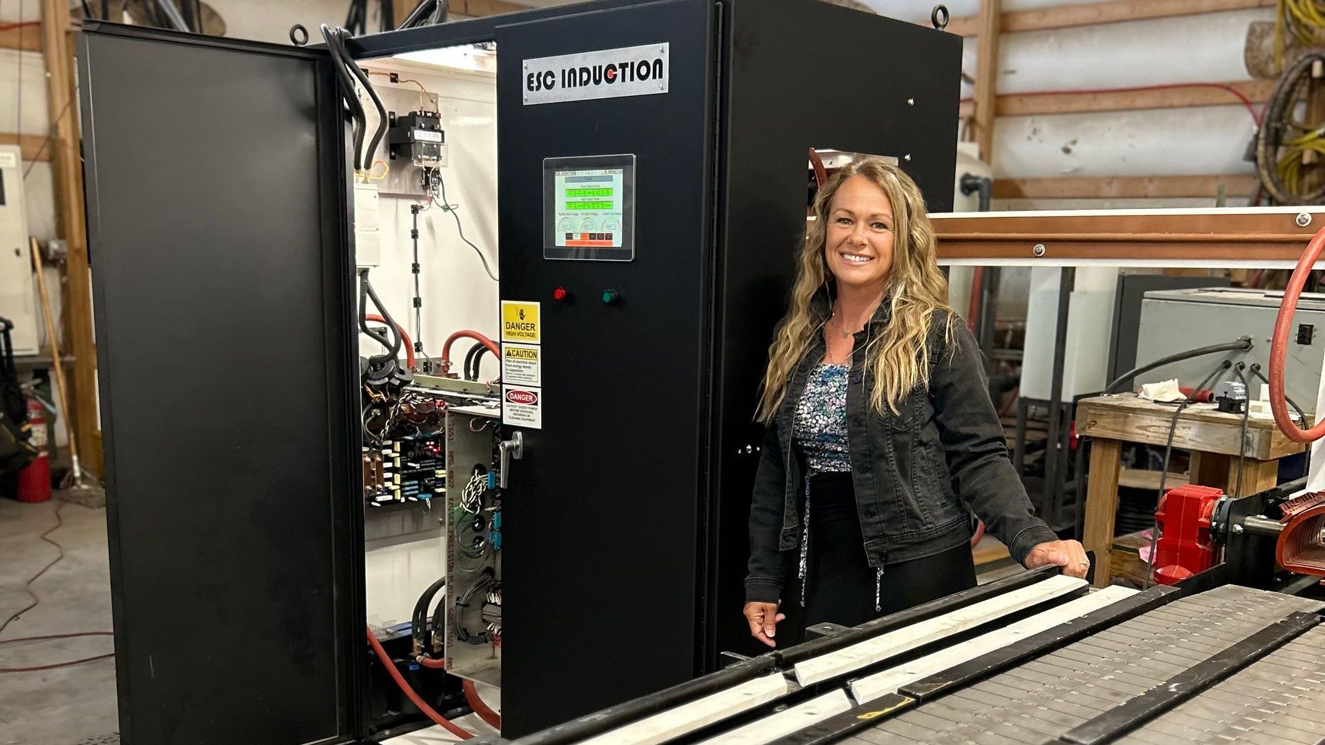 A woman is standing in front of a machine in a factory.