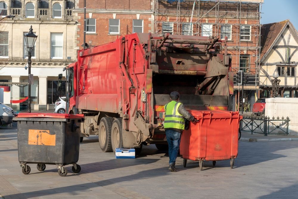 A Man is Loading Garbage Into a Garbage Truck — Anderson Waste Services in Mittagong, NSW
