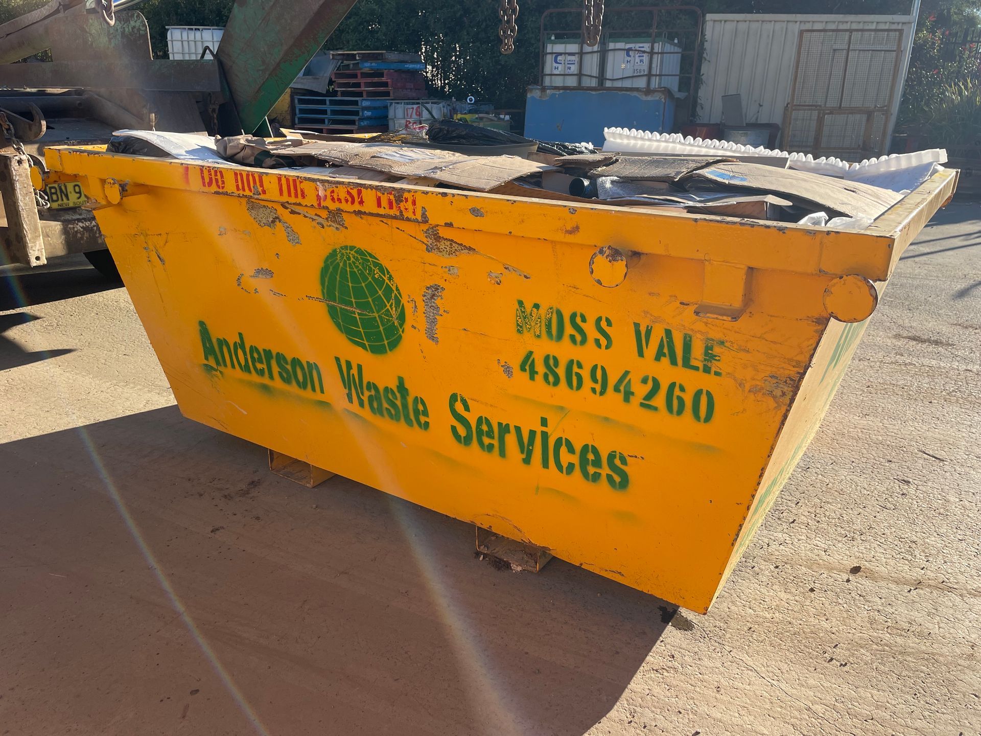 A Yellow Dumpster is Sitting in a Parking Lot Full Of Rubbish — Anderson Waste Services in Picton, NSW
