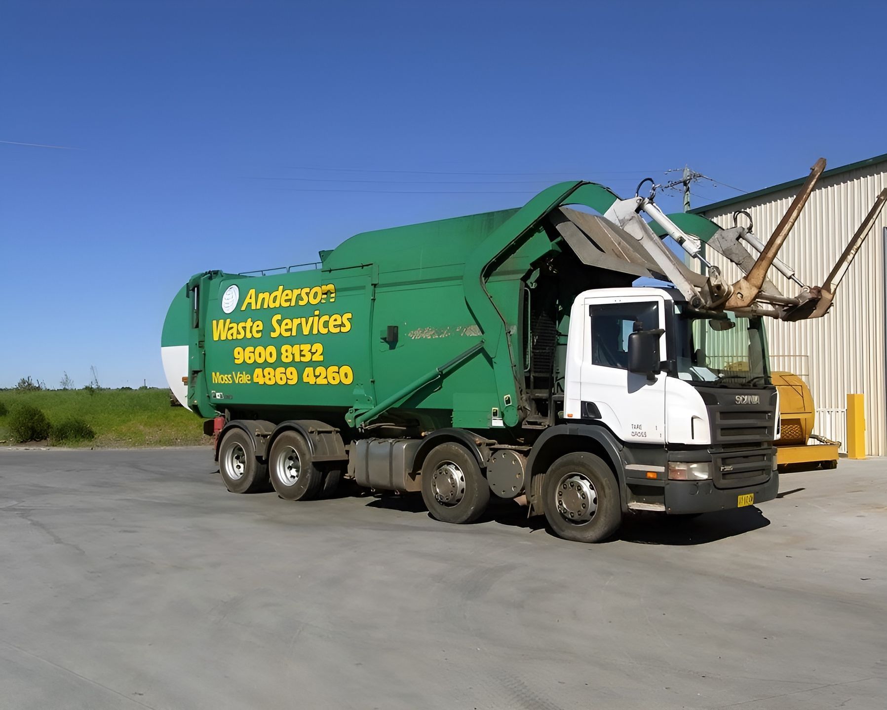 A green garbage truck is parked in front of a building — Anderson Waste Services in Picton, NSW