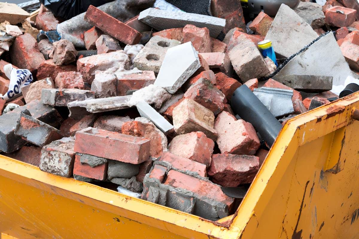 A Yellow Dumpster Filled With Bricks and Concrete — Anderson Waste Services in Moss Vale, NSW
