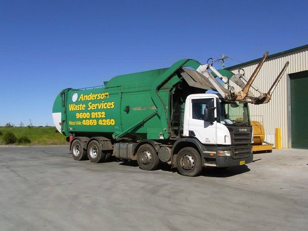 A Green Waste Services Truck is Parked in Front of a Building — Anderson Waste Services in Moss Vale, NSW