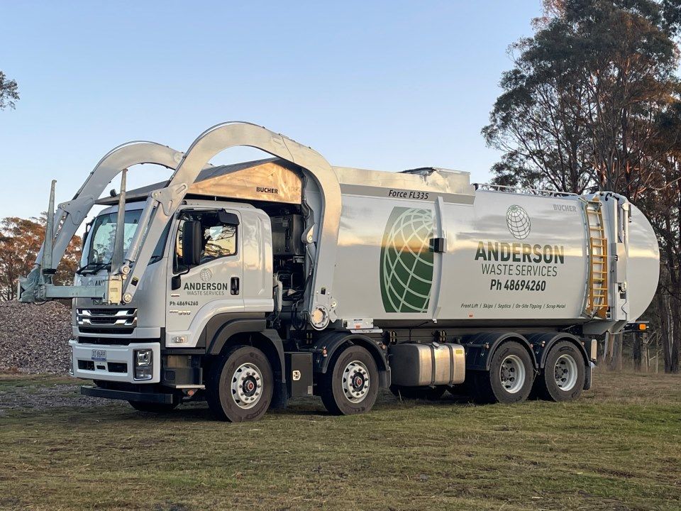 A Garbage Truck is Parked in a Grassy Field — Anderson Waste Services in Moss Vale, NSW