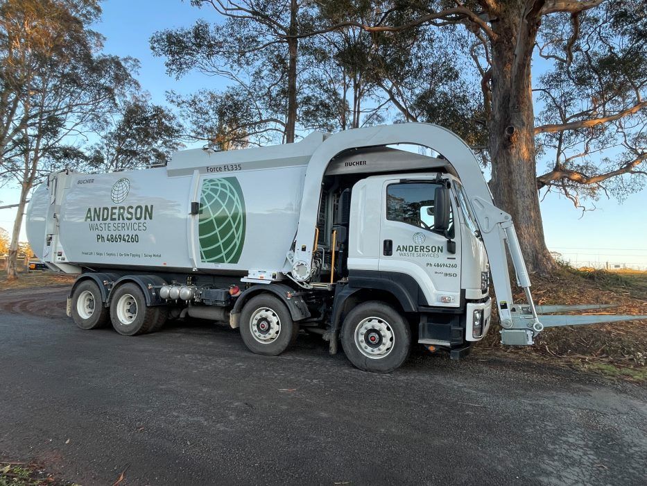 A Garbage Truck is Parked on the Side of the Road Next to a Tree — Anderson Waste Services in Moss Vale, NSW