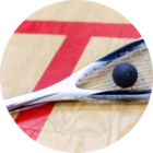 A close up of a squash racket and ball on a court