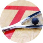 A close up of a squash racket and ball on a court