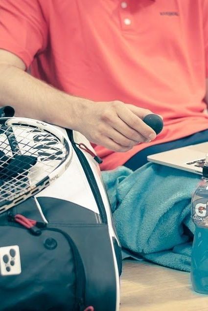 A man is holding a tennis racquet next to a gatorade bottle