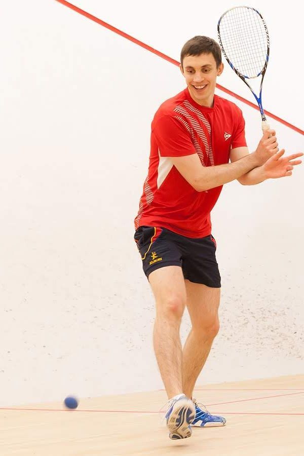 A man in a red shirt is holding a tennis racquet