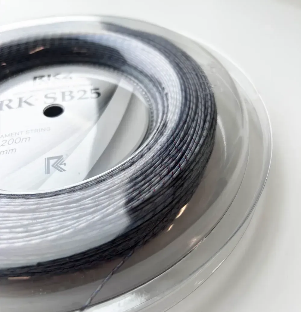 Spool of black tennis string inside a clear plastic container, brand name RK4, label visible.
