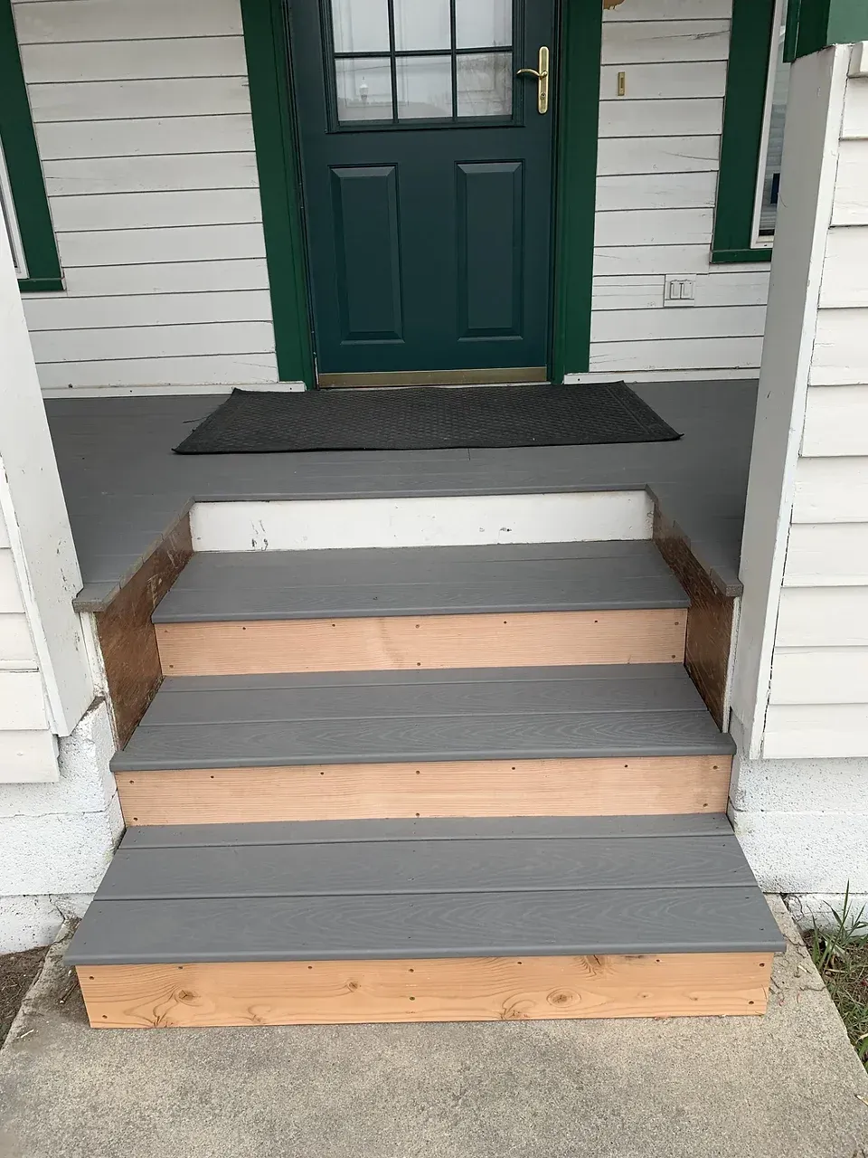 A set of wooden steps leading up to a front door of a house.