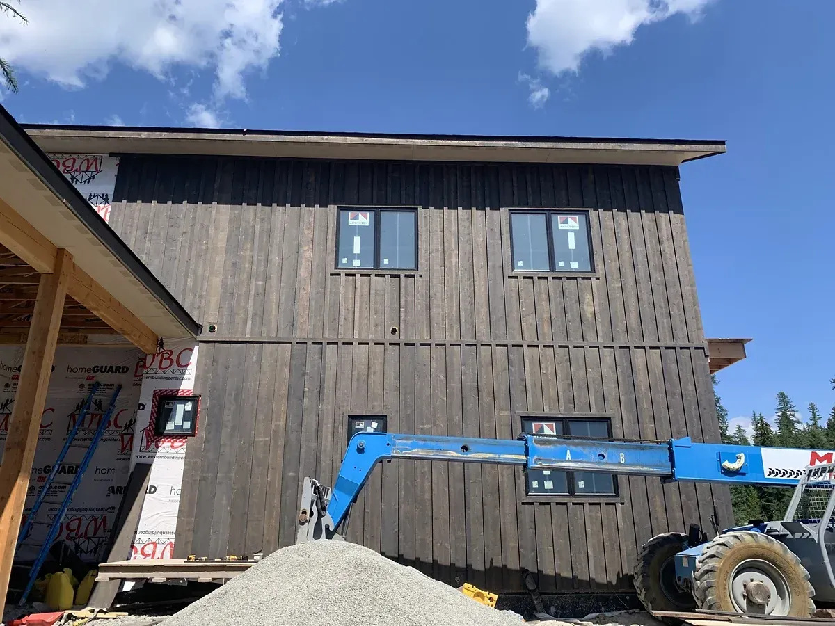 A blue crane is sitting in front of a building under construction.