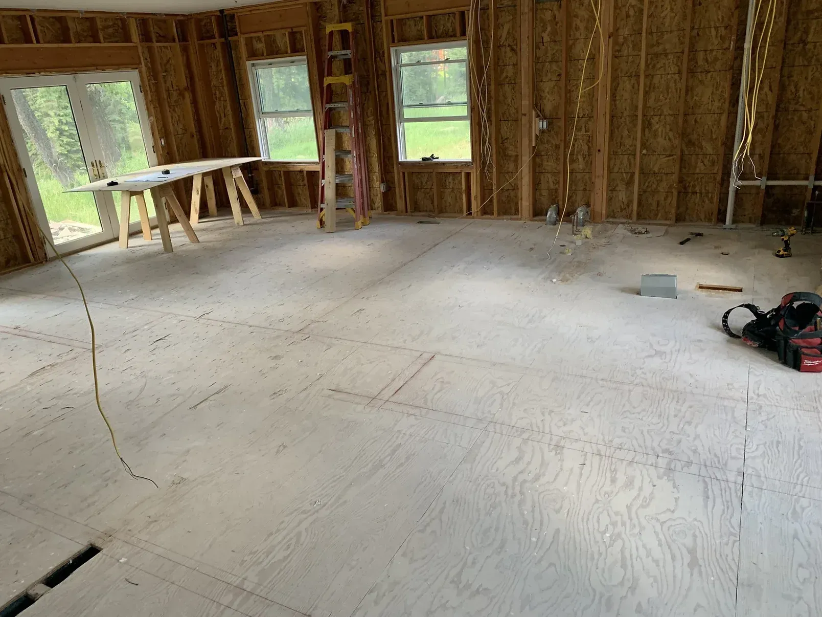 A room with a wooden floor and a ladder in it.