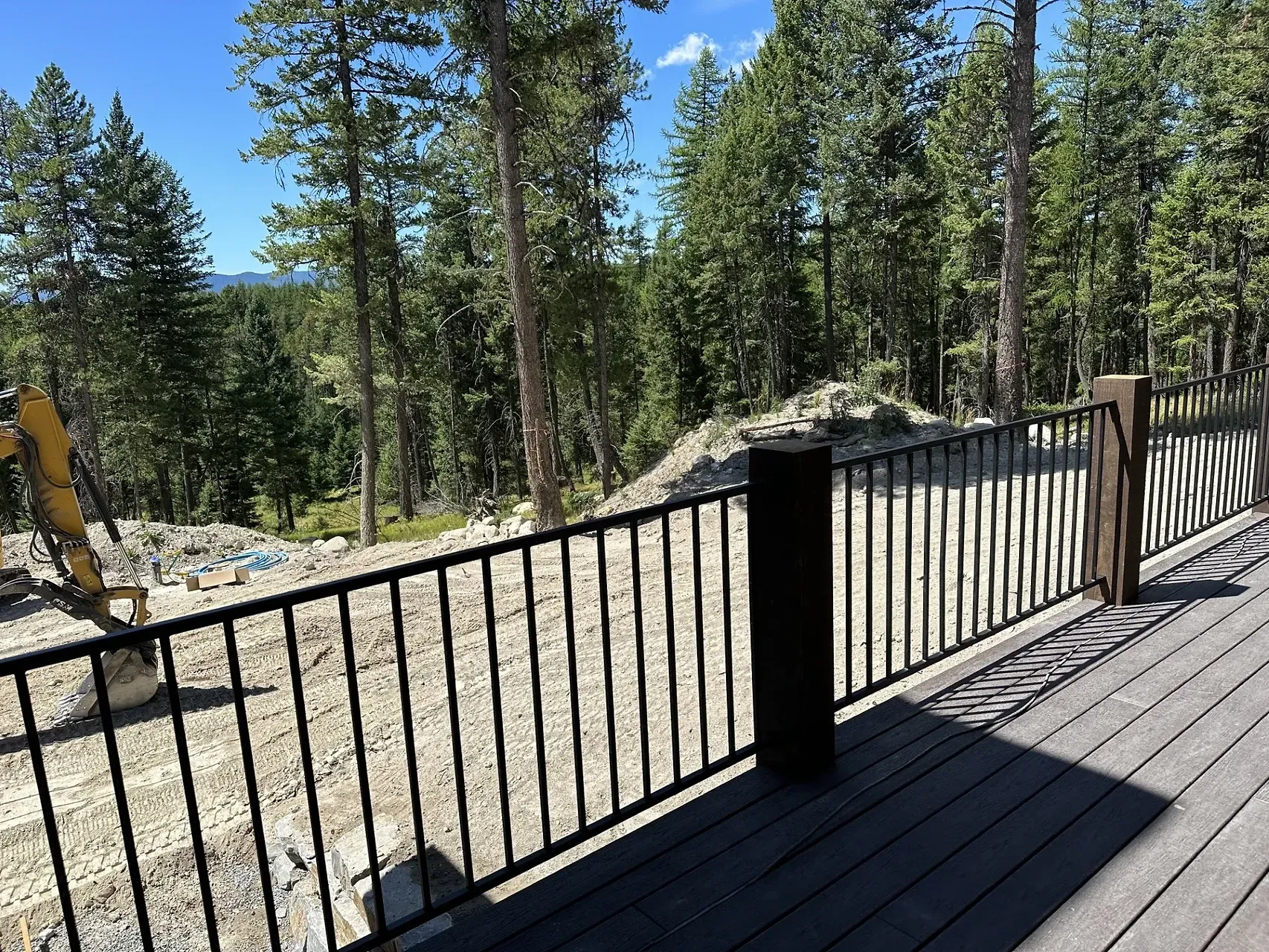 A deck with a fence and trees in the background