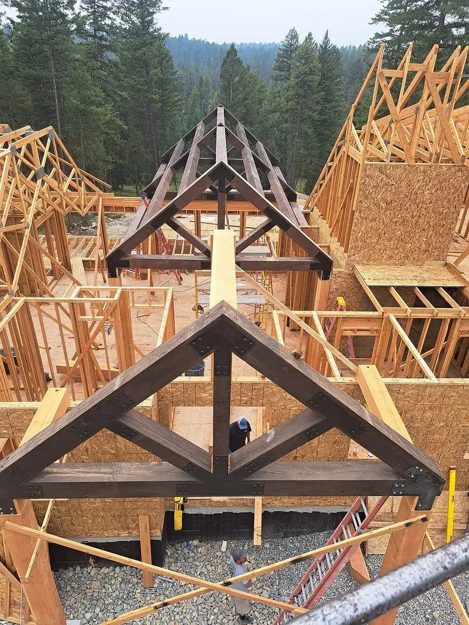 A large wooden structure is being built in the woods.
