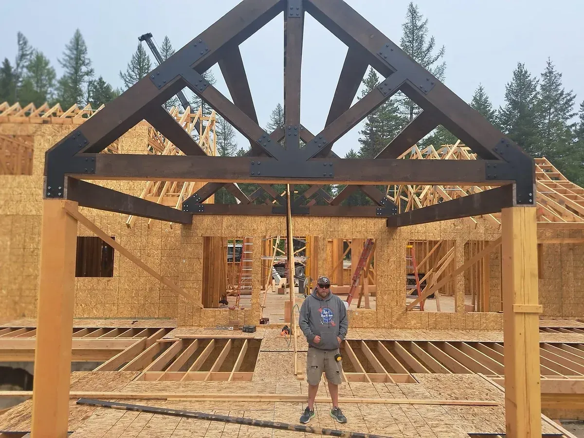 A man is standing in front of a wooden structure under construction.