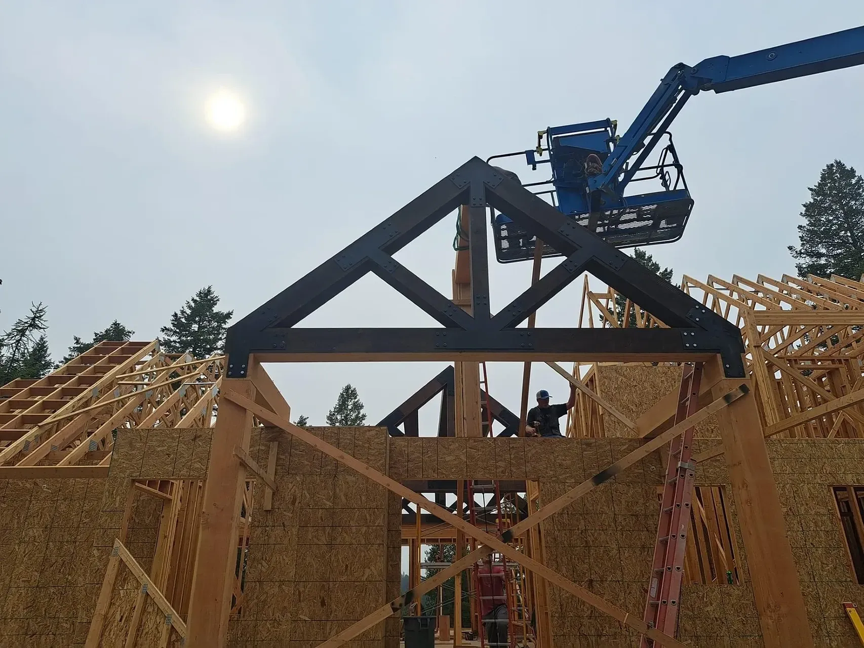 A crane is lifting a trusses on top of a wooden structure.