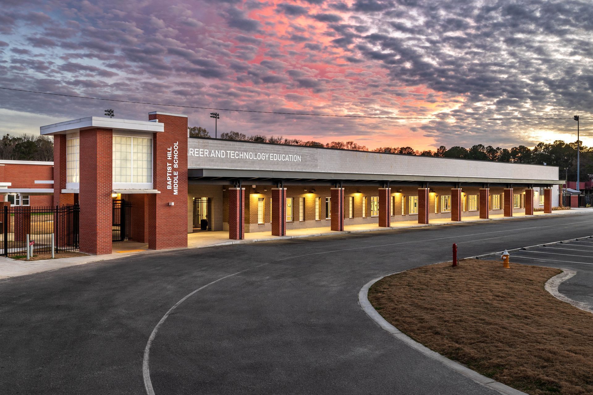 A large educational brick building with a sunset in the background