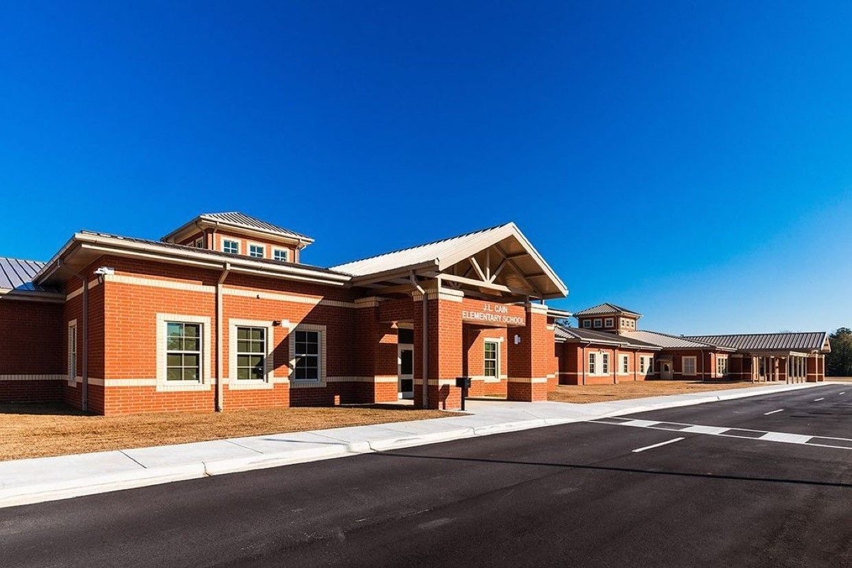 A large brick building, elementary school, showcasing parent drop off line